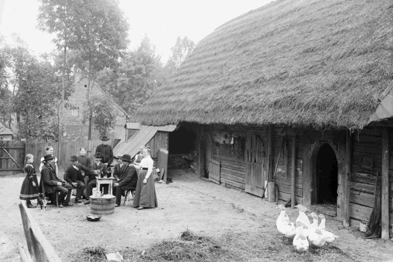 A family outside a thatched wooden house in an old Polish village