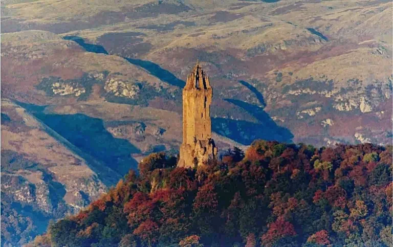 The Wallace Monument near Stirling, with autumn trees and the Ochil Hills behind it.